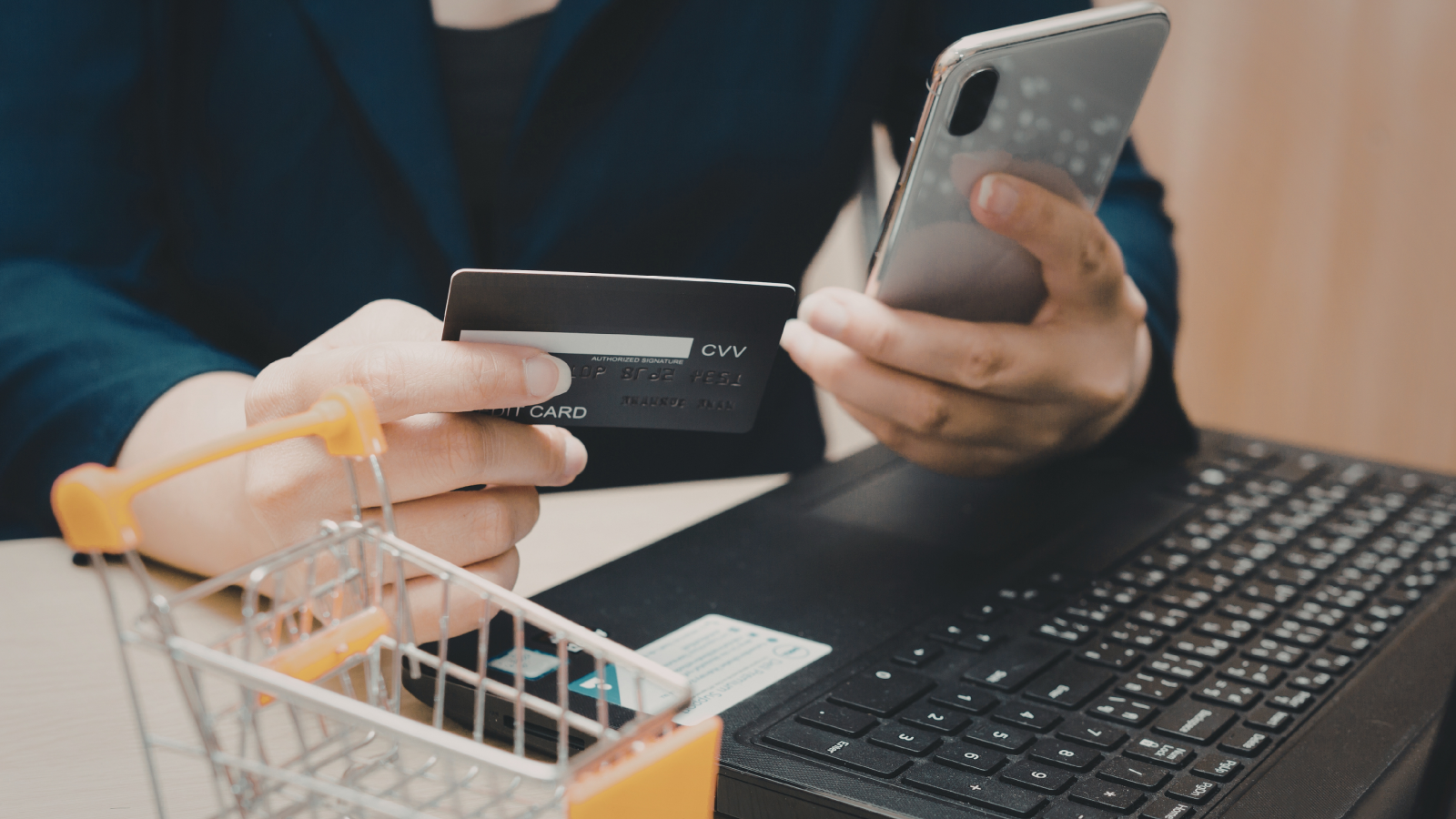 Online shopper checking a payment card and mobile phone before using a coupon code
